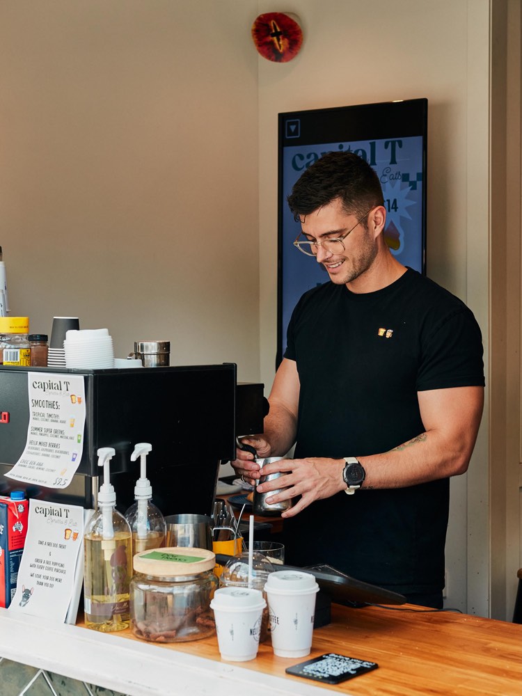 Tim steaming milk at the espresso machine inside the Capital T window.